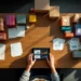 Business person organizing colorful product boxes on wooden desk with tablet showing analytics and shipping materials