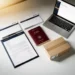 Belgian passport, business documents, laptop showing seller dashboard, and shipping box arranged as flat lay on white desk.