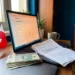 Polish złoty banknotes and VAT invoice on a laptop keyboard beside a small Polish flag, with Allegro seller dashboard on screen.