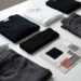 Folded black and white premium fashion garments beside a brand mood board with fabric swatches on a minimalist white surface.