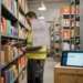 Magazijnmedewerker scant productdozen op metalen stellingen, met tablet met voorraaddata op nabijgelegen krat.