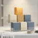Small product boxes arranged on a podium-style shelf, top box highlighted by warm spotlight, with shipping labels and measuring tape on a white warehouse surface.